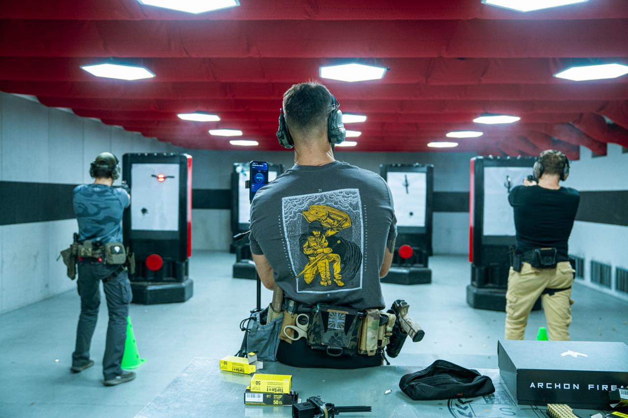 Back view of a shooter at an indoor pistol range with target booths